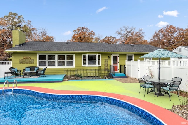 rear view of property with a shingled roof, a chimney, fence, and an outdoor living space