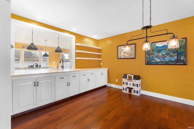 bar featuring recessed lighting, dark wood-style flooring, a sink, baseboards, and hanging light fixtures