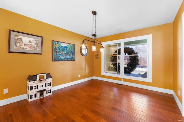 unfurnished dining area featuring visible vents, baseboards, and wood finished floors