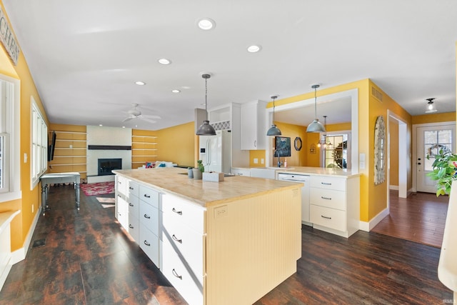 kitchen featuring white appliances, white cabinetry, light countertops, a center island, and pendant lighting