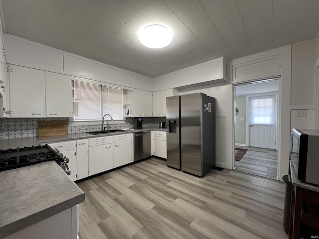 kitchen featuring appliances with stainless steel finishes, white cabinetry, a sink, and tasteful backsplash