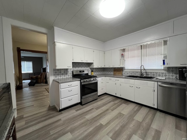 kitchen with white cabinetry, appliances with stainless steel finishes, backsplash, and a sink