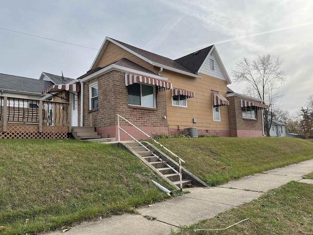 view of side of property with a deck, a lawn, and brick siding