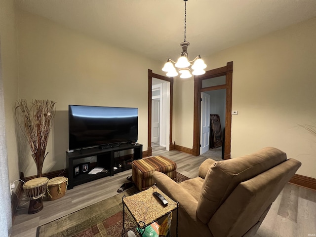 living area with baseboards, wood finished floors, and a notable chandelier