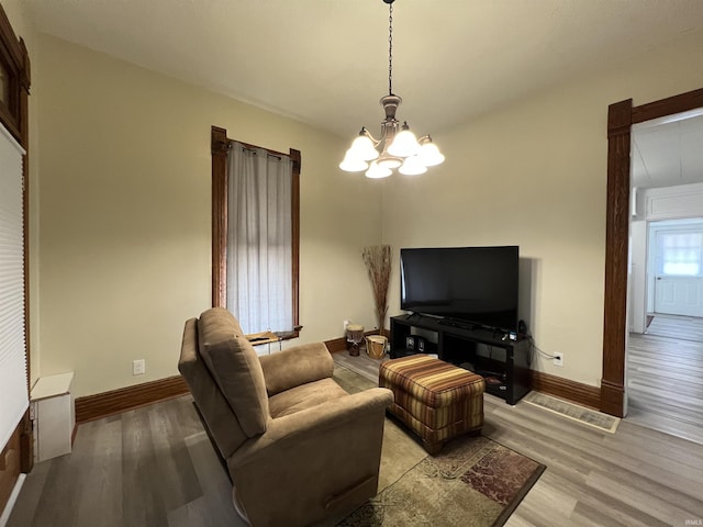 living area with light wood finished floors, baseboards, and an inviting chandelier