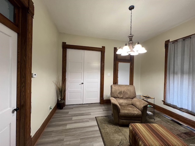 sitting room featuring a chandelier, light wood-style flooring, and baseboards