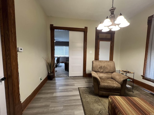 sitting room featuring a notable chandelier, baseboards, and wood finished floors