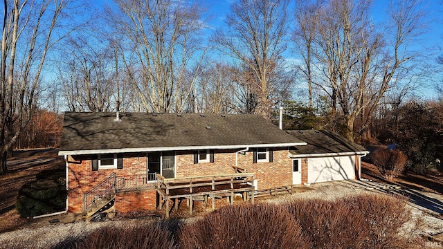 back of house featuring a garage, brick siding, driveway, and a shingled roof