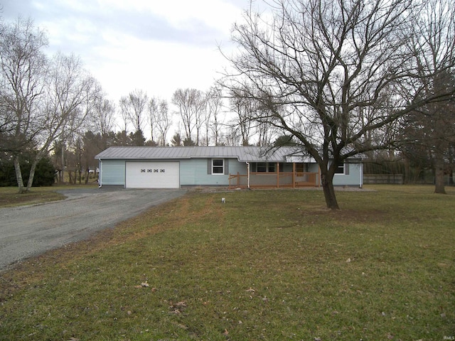 ranch-style home with a front yard, metal roof, driveway, and an attached garage