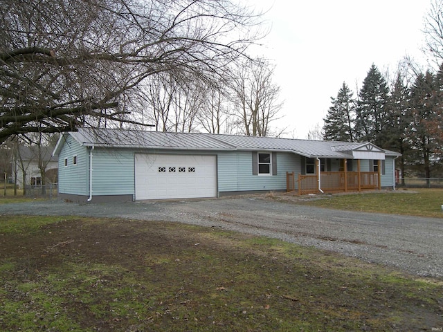 single story home with metal roof, aphalt driveway, a porch, a garage, and a standing seam roof