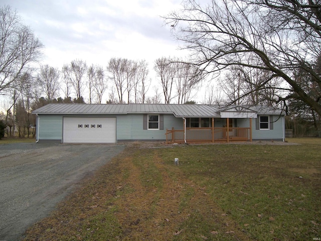 ranch-style house featuring metal roof, a porch, an attached garage, driveway, and a standing seam roof