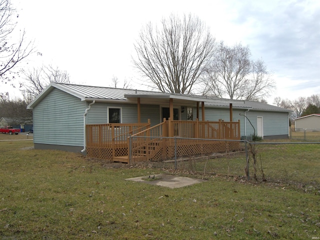 rear view of house with metal roof, a yard, a standing seam roof, and a wooden deck