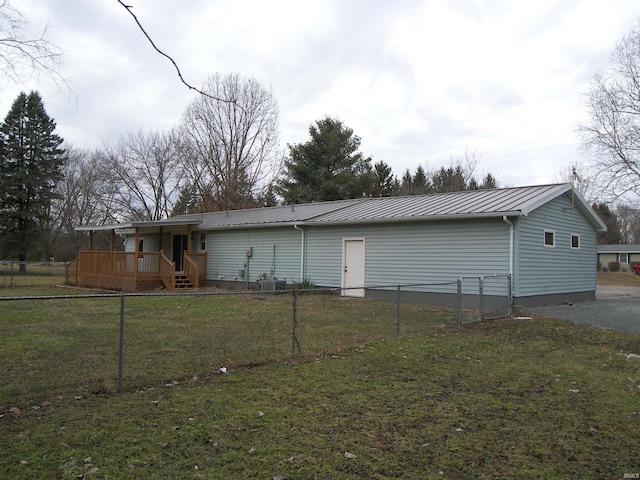 rear view of property with fence, metal roof, and a yard