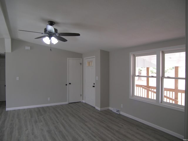 unfurnished room with dark wood finished floors, visible vents, a ceiling fan, vaulted ceiling, and baseboards