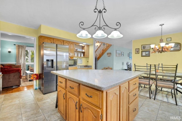 kitchen featuring a kitchen island, light countertops, stainless steel refrigerator with ice dispenser, black microwave, and pendant lighting