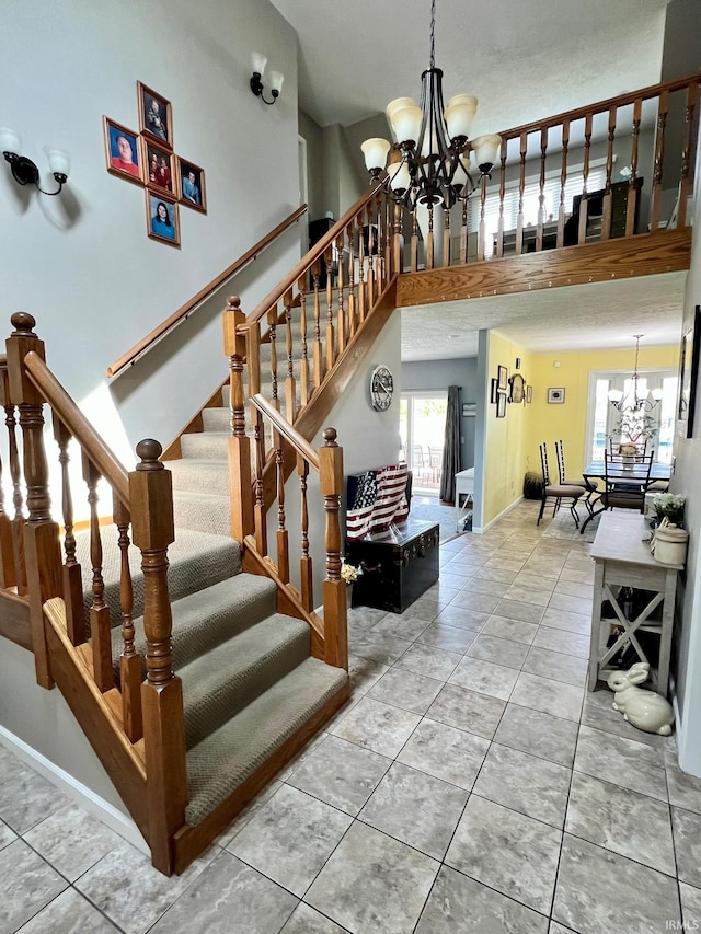 stairs featuring baseboards, a notable chandelier, a high ceiling, and tile patterned floors