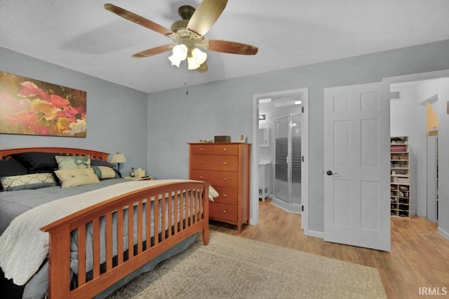 bedroom featuring light wood-type flooring, connected bathroom, baseboards, and a ceiling fan