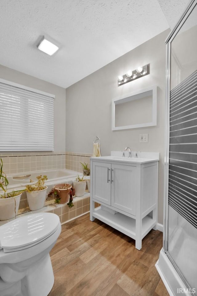 full bath with a textured ceiling, toilet, wood finished floors, vanity, and a shower stall