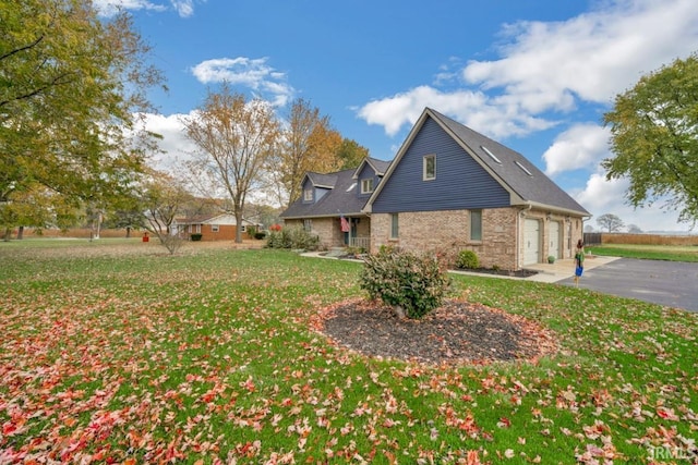 view of front of property with a garage, brick siding, driveway, and a front lawn