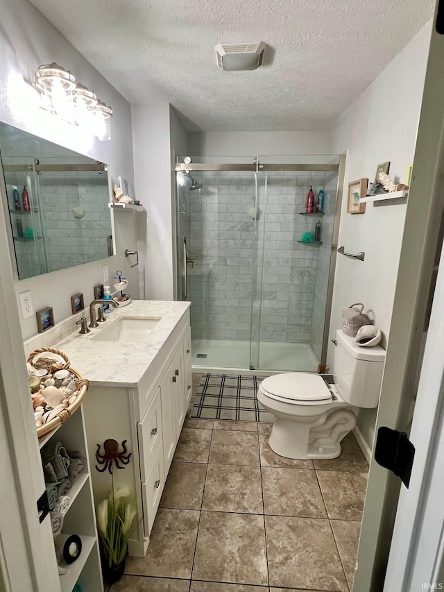 full bathroom featuring visible vents, toilet, vanity, a textured ceiling, and tile patterned flooring