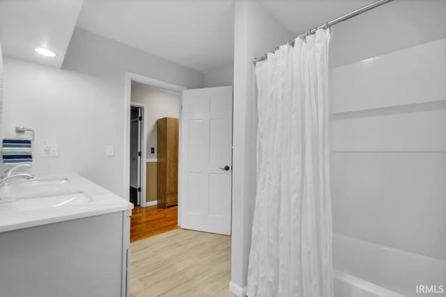 full bathroom featuring shower / bath combo with shower curtain, double vanity, a sink, and wood finished floors