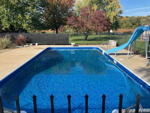 view of swimming pool featuring a patio area, fence, a diving board, and a water slide