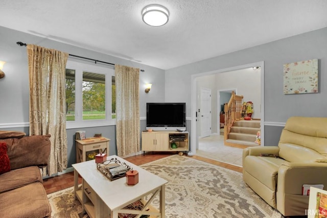 living area with stairs and a textured ceiling