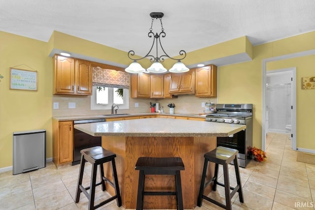 kitchen with a sink, stainless steel range with gas cooktop, a kitchen island, and dishwasher