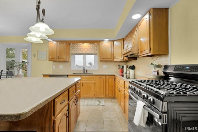 kitchen with range with gas stovetop, backsplash, light countertops, pendant lighting, and a sink