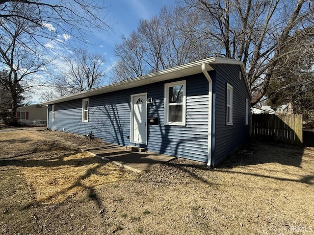 view of front of home featuring entry steps, fence, and a front lawn