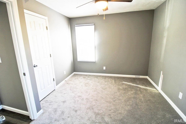 carpeted spare room with ceiling fan and baseboards