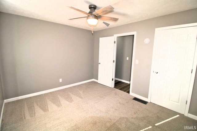 unfurnished bedroom featuring baseboards, a closet, dark carpet, and a ceiling fan