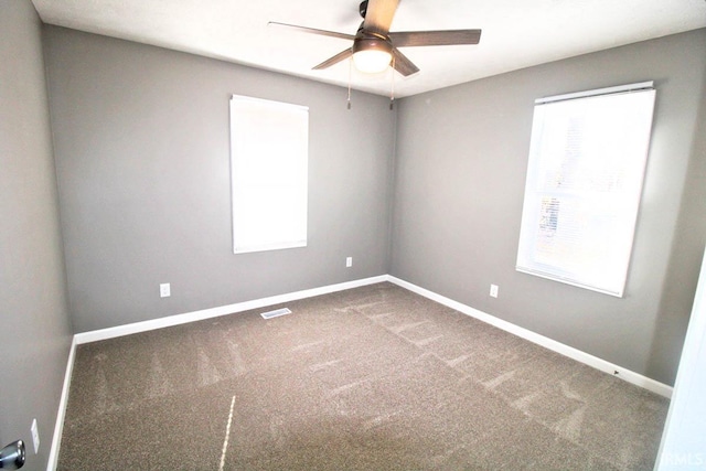 empty room with carpet, visible vents, ceiling fan, and baseboards