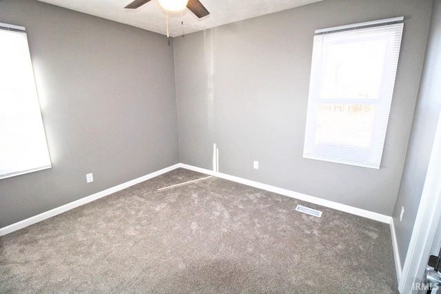 carpeted empty room featuring baseboards, visible vents, and a ceiling fan