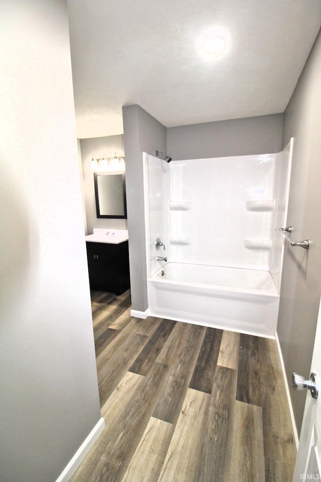 bathroom featuring shower / bathing tub combination, wood finished floors, vanity, and baseboards