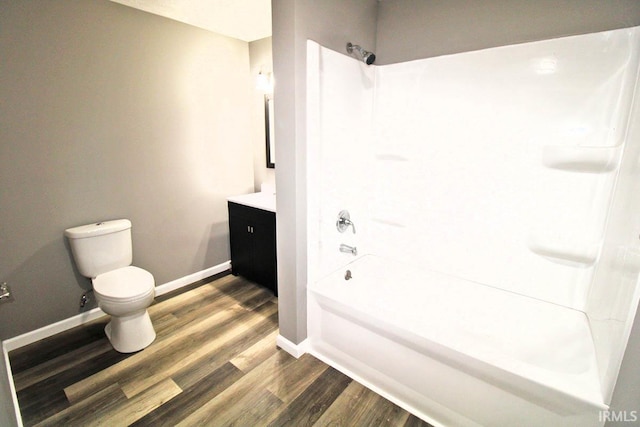 full bathroom with toilet, washtub / shower combination, vanity, wood finished floors, and baseboards