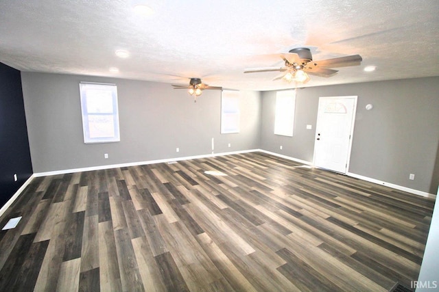 empty room with a ceiling fan, a textured ceiling, baseboards, and dark wood-style flooring