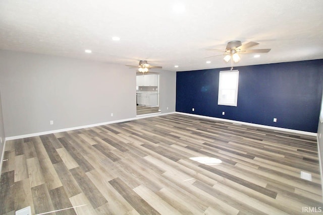 empty room with light wood-style floors, recessed lighting, a ceiling fan, and baseboards