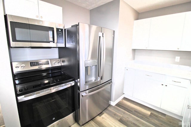 kitchen featuring stainless steel appliances, light countertops, and white cabinets