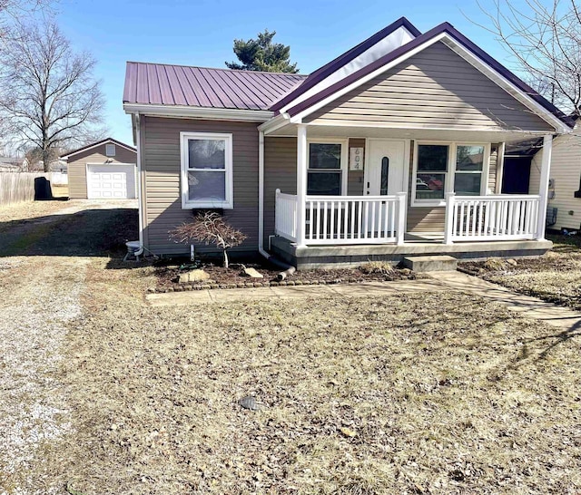 bungalow with driveway, metal roof, a porch, and an outdoor structure