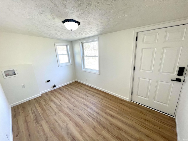 interior space with light wood-style flooring, baseboards, and a textured ceiling