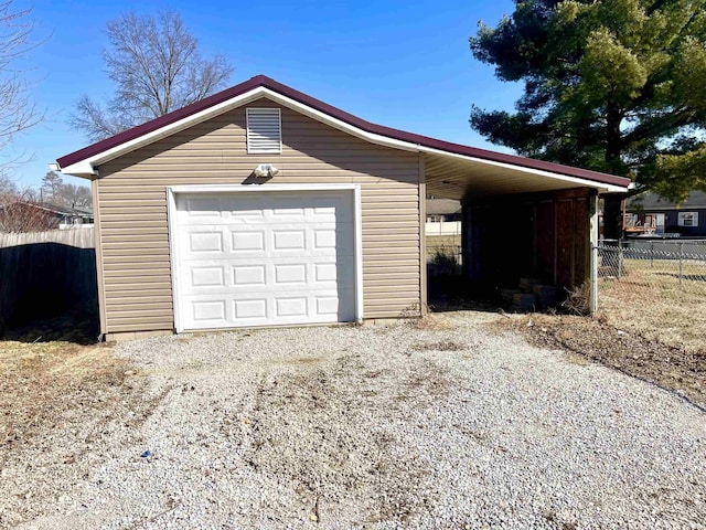 garage featuring a garage, driveway, and fence