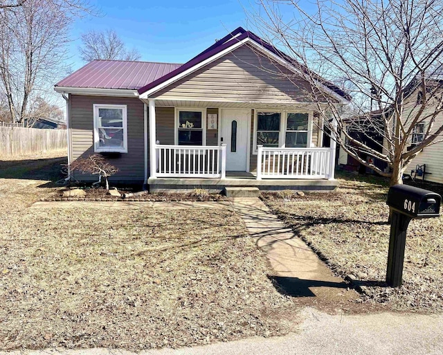 bungalow-style home with metal roof, fence, and a porch