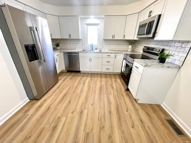 kitchen featuring visible vents, light wood-style floors, white cabinets, appliances with stainless steel finishes, and light stone countertops