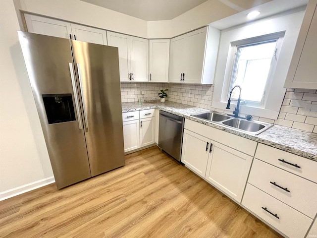 kitchen featuring appliances with stainless steel finishes, light wood-style floors, white cabinetry, and a sink