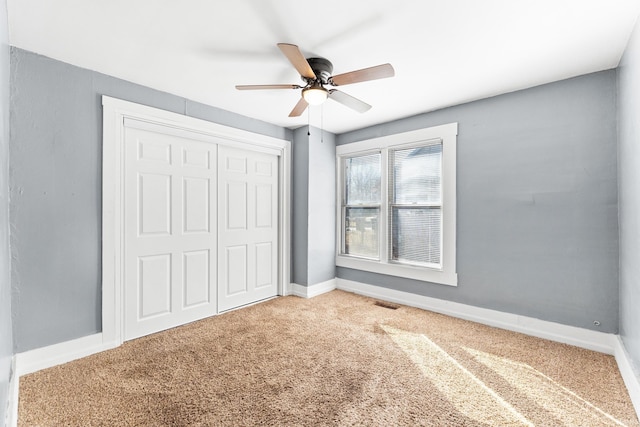 unfurnished bedroom featuring carpet floors, a closet, visible vents, ceiling fan, and baseboards