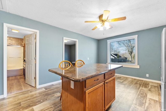 kitchen featuring dark countertops, light wood-style floors, brown cabinetry, and a center island