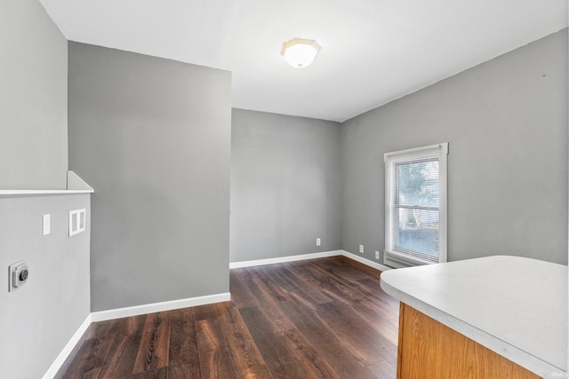 unfurnished room with baseboards and dark wood-style flooring