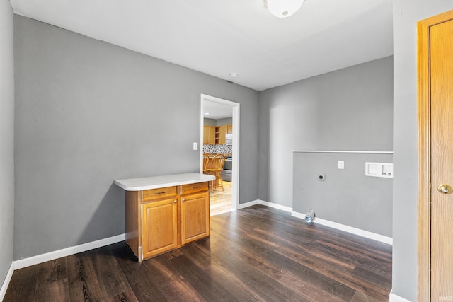 washroom featuring dark wood-style flooring, hookup for a gas dryer, cabinet space, electric dryer hookup, and baseboards