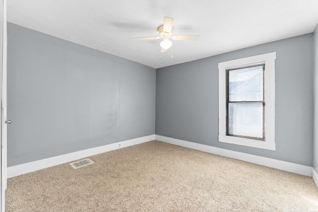 carpeted spare room with ceiling fan, visible vents, and baseboards